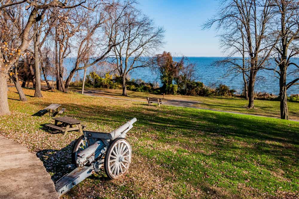 Historic artillery rests in a peaceful park overlooking the serene waters.
