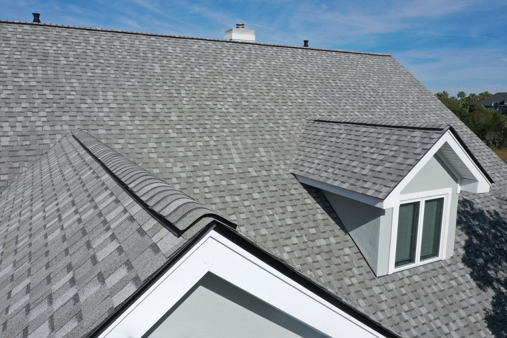 High-angle view of a professionally installed asphalt shingle roof with a dormer window, being assessed for integrity and durability by Next Day Inspect.