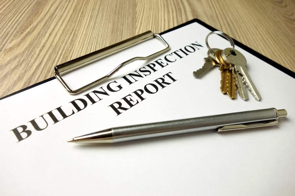 Building inspection report with pen and house keys on a wooden desk, ready for review.