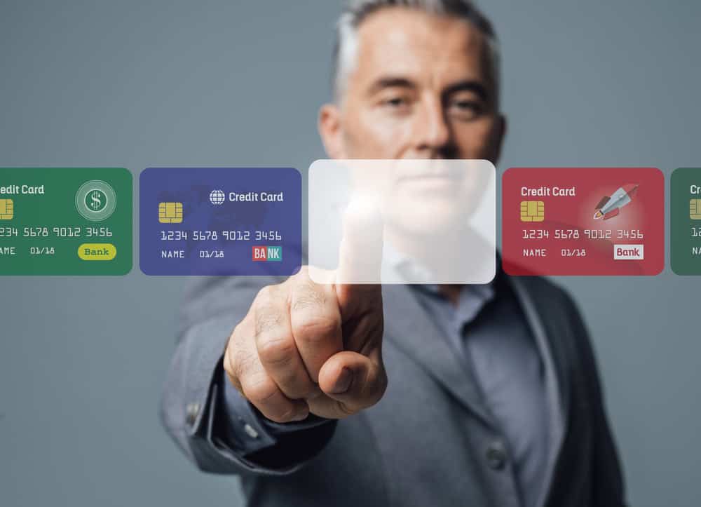 Businessman selecting a virtual credit card from a futuristic digital interface.