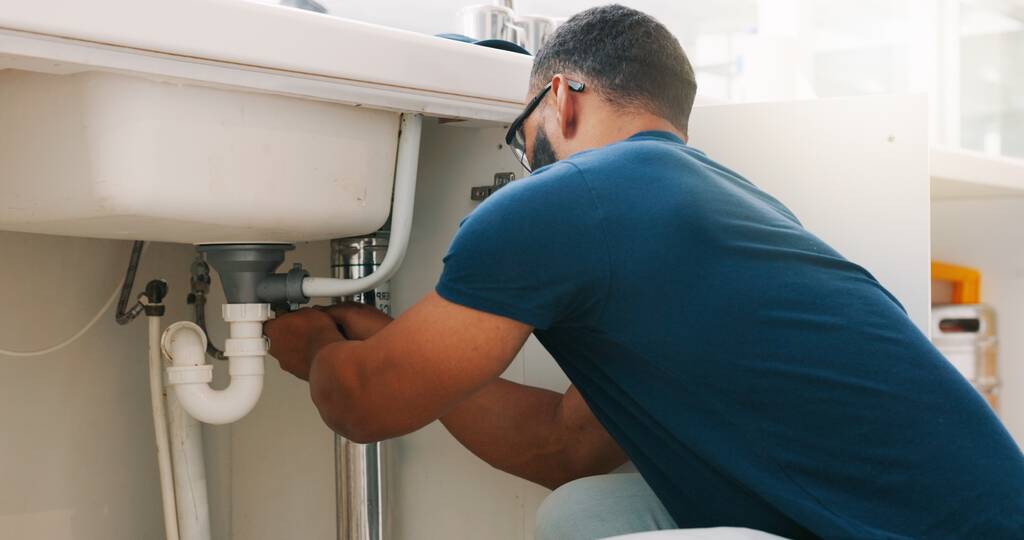 Plumber or DIYer inspecting a sink P-trap