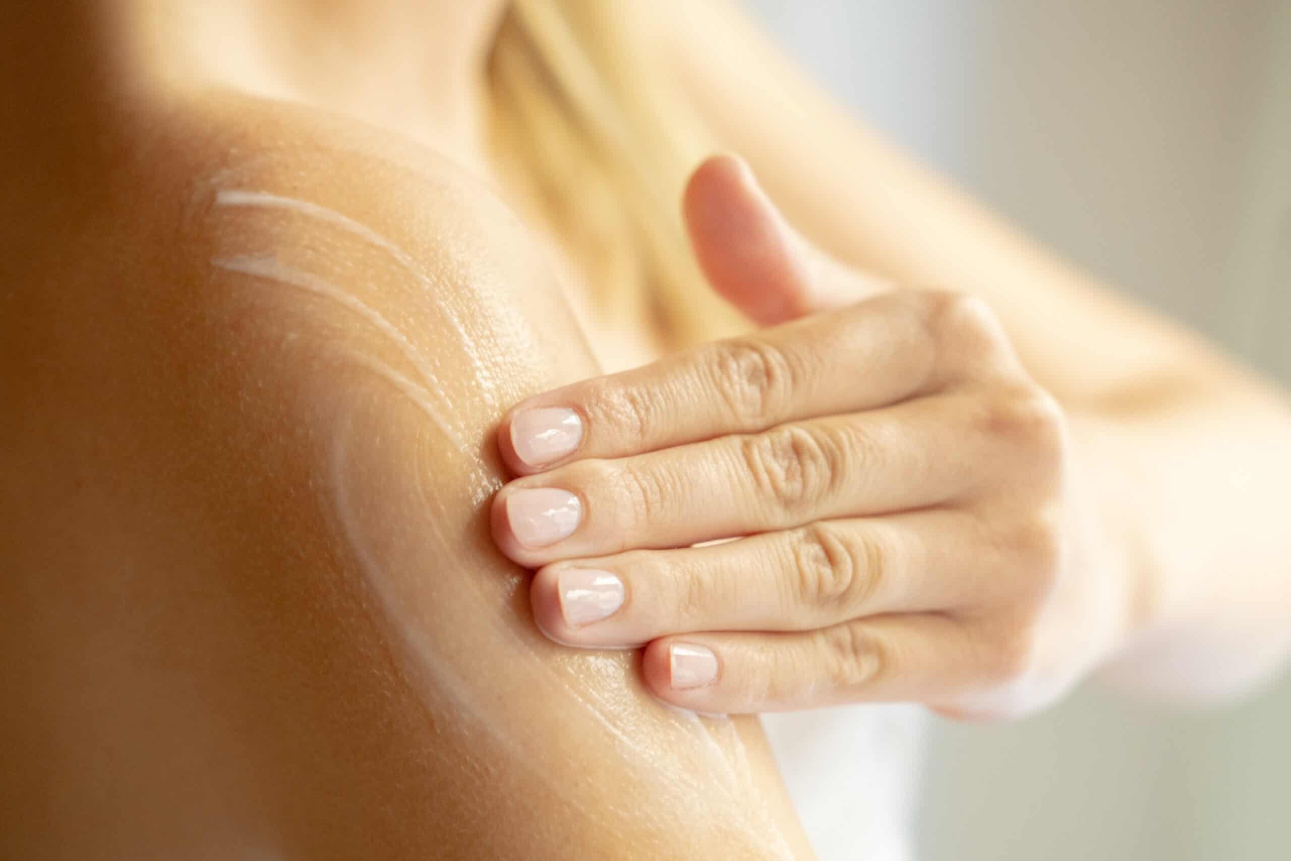 Body skin care after the shower, a young woman applies a moisturizing lotion on her shoulder. Female Beauty routine