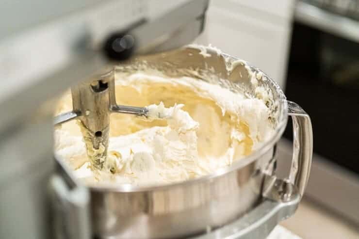 Cream being mixed in a stainless steel dairy equipment bowl for ice cream or dairy products preparation.