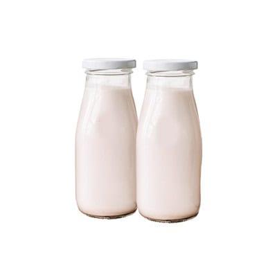 Glass bottles of fresh milk showcasing NK Dairy Equipments' dairy product packaging solutions.