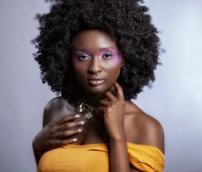 Beautiful African Woman with big curly  Afro and flowers in her hair. the black female model is wearing the pink make-up happily