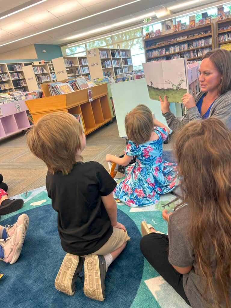 Enjoying a storytime session at a public library, children listen attentively as a librarian reads a colorful picture book aloud, fostering early literacy and a love for books.