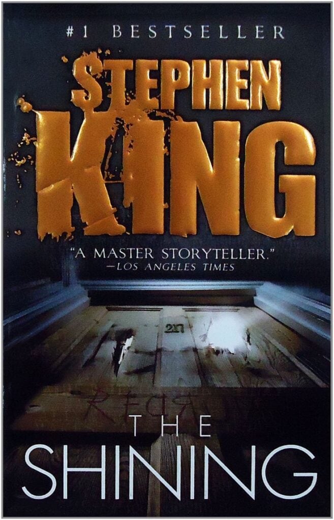 Stephen King book cover, horror novel "The Shining" with dark house and wooden door imagery, ideal for horror literature and suspense fiction lovers.
