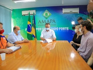 Ampá representante do governo do estado do Tocantins participa de reunião com autoridades, discutindo ações ambientais e de desenvolvimento sustentável, com bandeiras do Brasil, Tocantins e ambientalismo ao fundo.