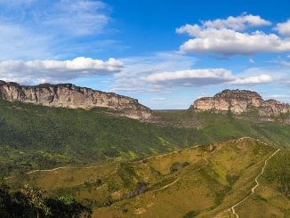 Montanhas e vale na região de Chapada dos Guimarães, em Mato Grosso, paisagem de natureza exuberante com céu azul, nuvens e vegetação densa.