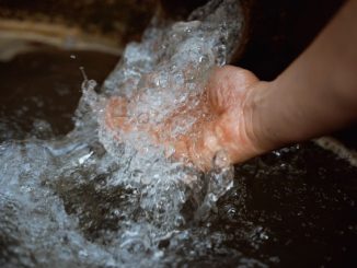 Água limpa sendo segurada na mão, simbolizando preservação e sustentabilidade ambiental.