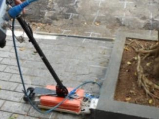 Instrumento de inspeção ambiental realizando análise em calçada com árvore em ambiente urbano.