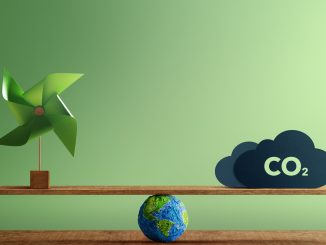 Árvore de papelão e máquina de vento ecológica com modelo do planeta Terra apoiado em uma régua de madeira, destacando equilíbrio ambiental, sustentabilidade e redução de emissões de CO2.