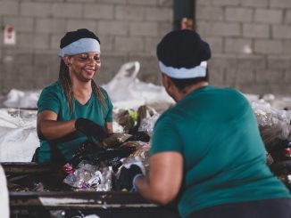 Recicladores trabalhando com resíduos plásticos em instalação de coleta de lixo, promovendo sustentabilidade e gestão ambiental eficiente.