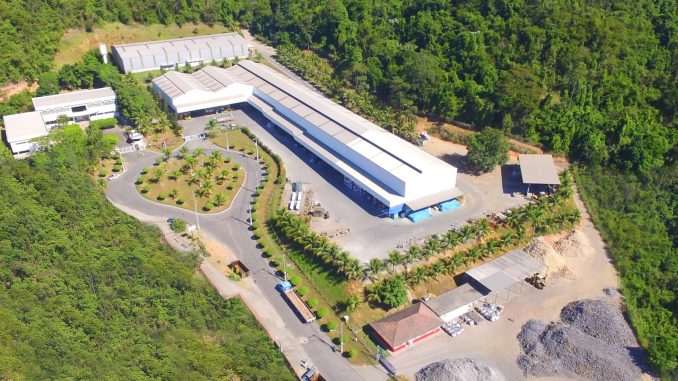 Fachada de instalação industrial sustentável cercada por área verde e árvores, destacando conceitos de preservação ambiental e gestão ambiental empresarial.