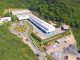 Fachada de instalação industrial sustentável cercada por área verde e árvores, destacando conceitos de preservação ambiental e gestão ambiental empresarial.