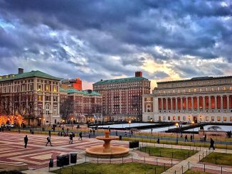 Edifícios históricos e modernos ao pôr do sol na cidade de Denver com nuvens dramáticas no céu. Paisagem urbana com pessoas caminhando, iluminação e área de lazer ao ar livre.