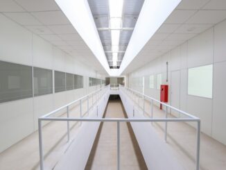 Corredor interno de instalações industriais modernas com iluminação eficiente, destaque para praticidade, segurança e otimização de espaços. Design clean e funcional para ambientes corporativos.