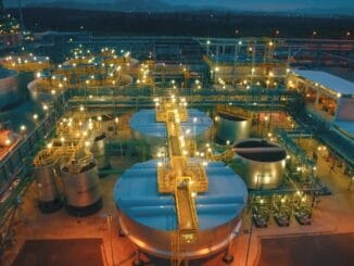 Tanque de armazenamento de petróleo industrial iluminado à noite, foco em infraestrutura de refinaria de petróleo, destaque para plantas industriais e sistemas de processamento de combustíveis.