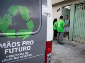 Caminhão de logística reversa com símbolo de reciclagem e equipe de coleta ambiental na frente de residência, promovendo práticas sustentáveis e inovação ambiental.