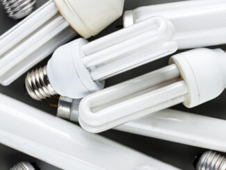 Lâmpadas fluorescentes de baixo consumo acumuladas, foco em sustentabilidade e descarte correto de resíduos eletrônicos.