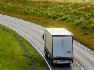Caminhão em estrada rural com vegetação exuberante ao redor, destacando transporte sustentável e logística ambientalmente responsável.