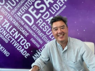 Inovador, jovem empresário sorridente em ambiente corporativo com fundo inspirado em palavras relacionadas ao mundo dos negócios e sustentabilidade, destaque para ambiente profissional moderno.