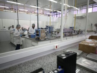 Mão de obra em laboratório de controle de qualidade ambiental, com profissionais usando roupas de proteção, analisando amostras em ambiente industrial limpo.