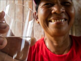 A0001.jpg - Mulher idosa sorridente segurando um copo de água, promovendo saúde e bem-estar, imagem que destaca a importância do consumo hídrico para a saúde, conceito de sustentabilidade e qualidade de vida.