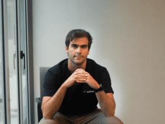 Homem sério sentado assim em uma sala de reunião com janelas ao lado, vestindo camiseta preta com logo da Volterra, ambiente corporativo, foco em sustentabilidade e negócios ambientais, imagem profissional ambiental mercantil.