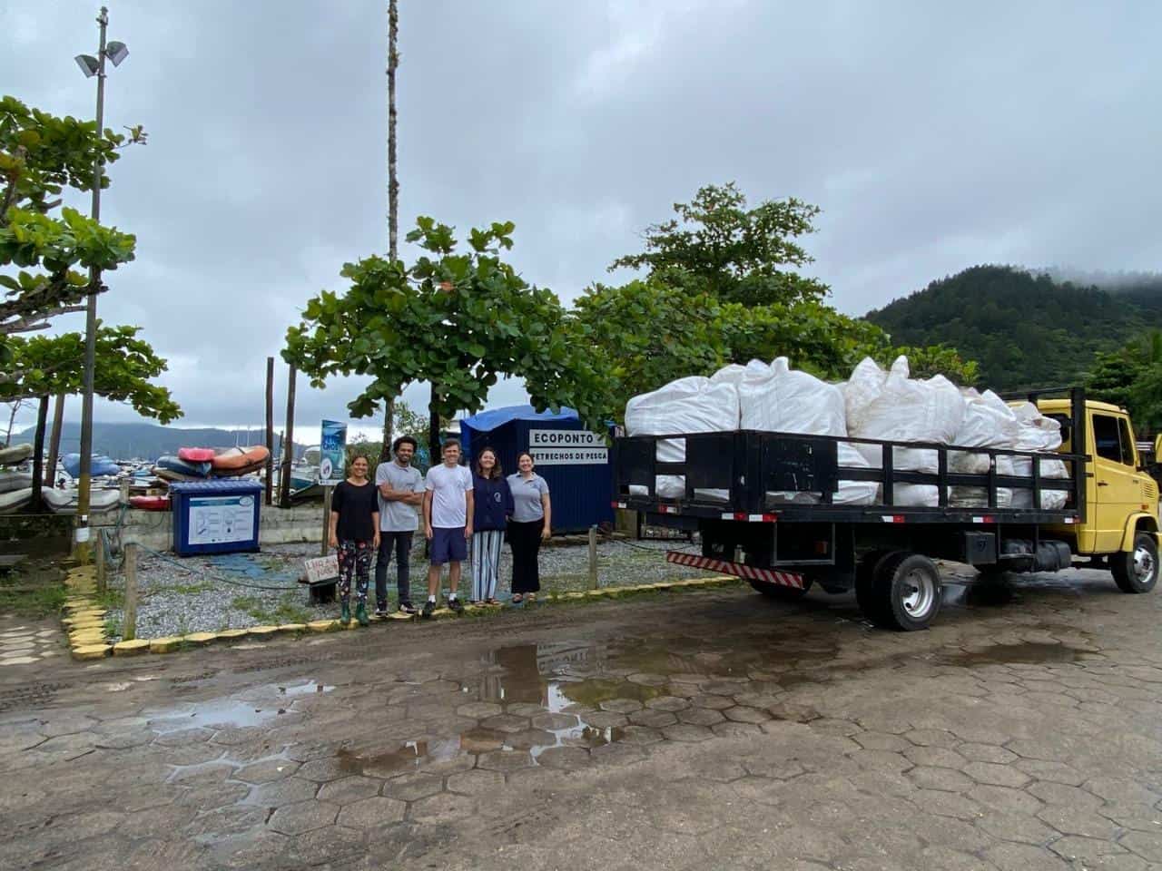 Caminhão de coleta de resíduos de pescados na área de lazer com equipe mostrando a dedicação à gestão de resíduos pesqueiros.
