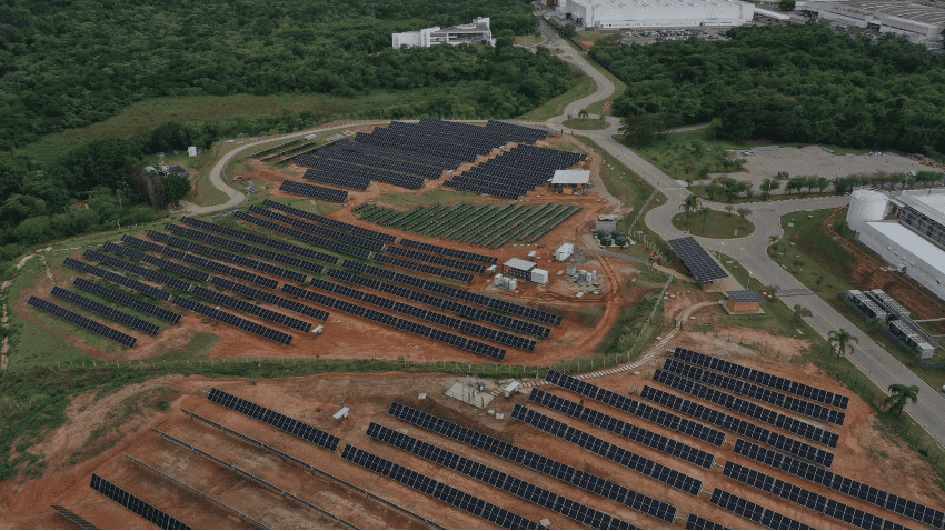 Painel solar em instalação de grande porte em ambiente de área verde, promovendo energia limpa e sustentável. Fotografia aérea de parque de energia solar com painéis fotovoltaicos.