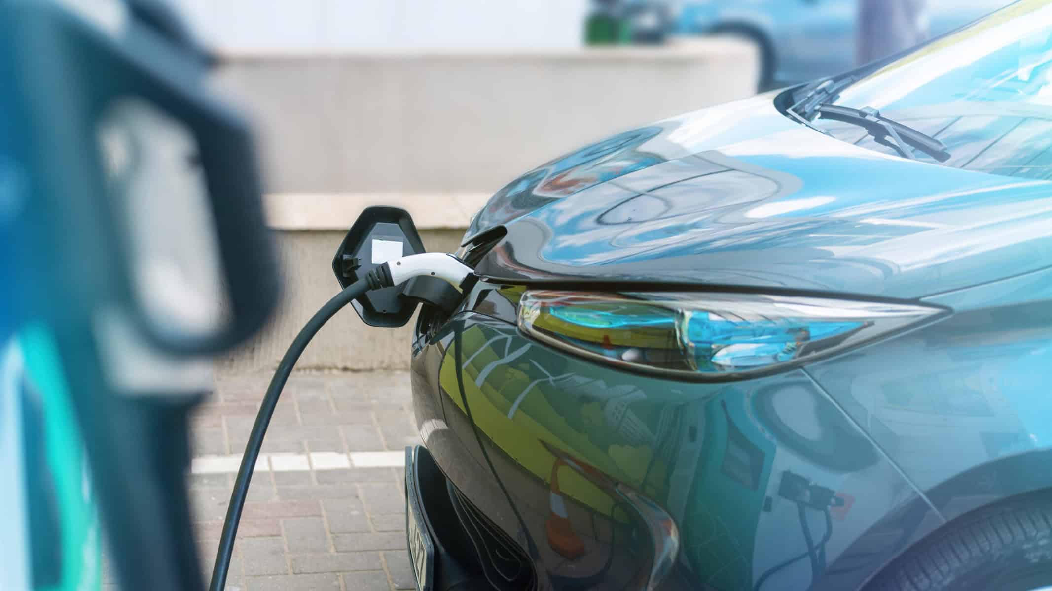 Carro elétrico sendo carregado em estação de recarga, veículo sustentável e inovação em mobilidade elétrica, promovendo redução de emissões e energias renováveis.