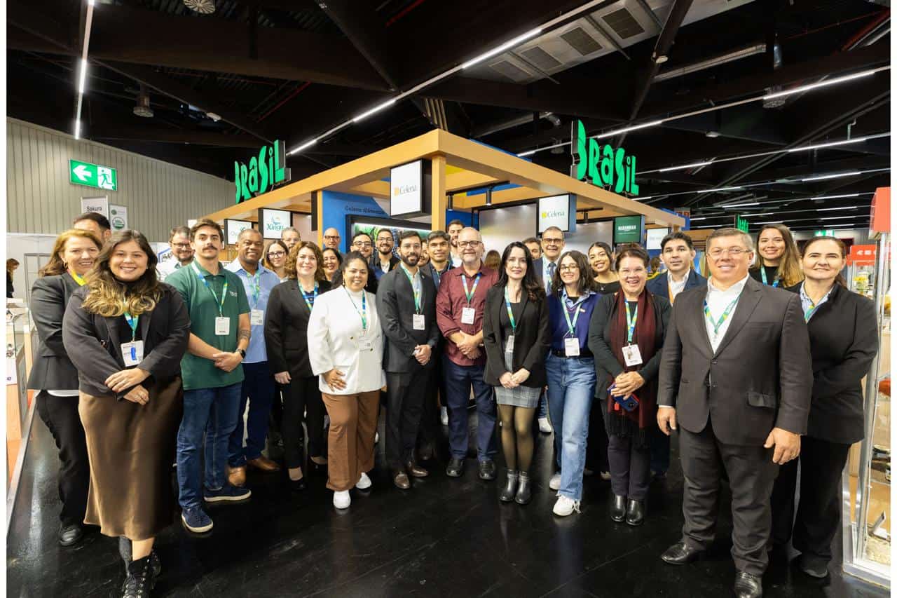 Celebrando networking e inovação na feira ambiental com equipe diversificada, destacando compromisso sustentável, tecnologia e colaboração no setor ambiental e mercantil.