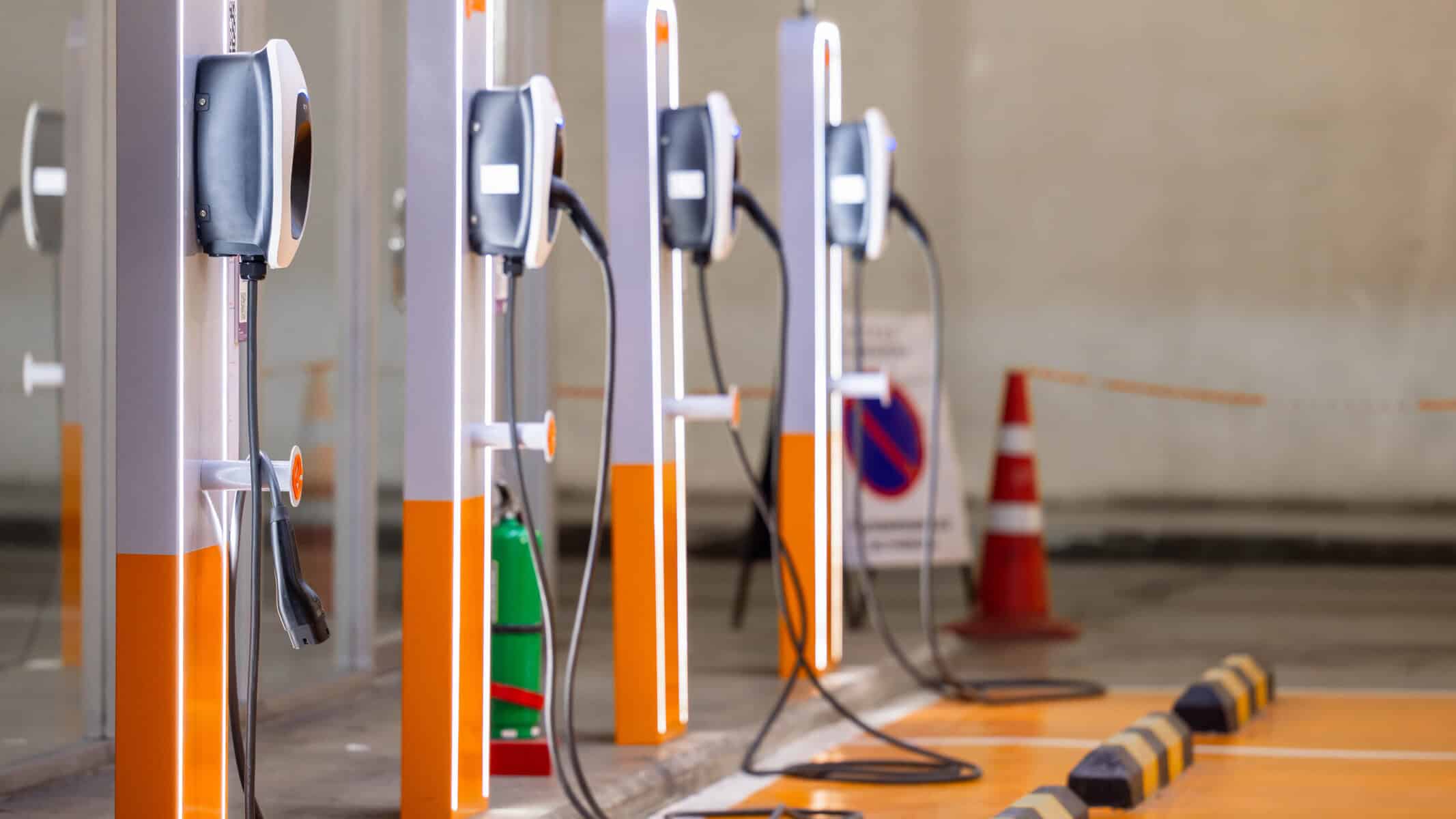 Estação de carregamento de veículos elétricos em um estacionamento, destaque para os pontos de recarga modernos e sustentáveis, promovendo a mobilidade elétrica e o cuidado ambiental.