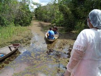 Mulheres navegando por rio com vegetação densa, foco em preservação ambiental e comunidades tradicionais, promovendo sustentabilidade e ecoturismo na região amazônica.
