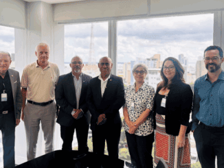 Profissionais em reunião de negócios ambientais em ambiente corporativo com vista para a cidade ao fundo.