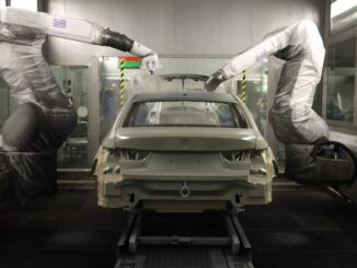 Robôs industriais inspecionando carroceria de veículo em linha de montagem.