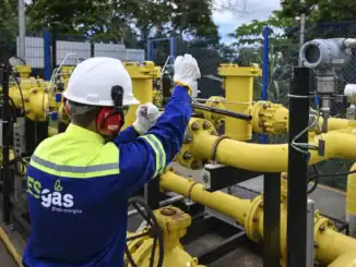 Tanque de gás natural com técnico realizando manutenção em instalações industriais de energia.
