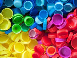 Cores variadas de tampas de plástico recicladas, simbolizando sustentabilidade e reciclagem de materiais plásticos.