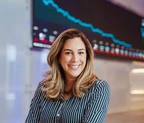 Gráfica de desempenho financeiro em fundo de tela de centro de negócios, mulher sorridente demonstrando confiança na gestão de investimentos e análise de mercado.