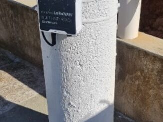 Postes de proteção de hidrantes de concreto pintados de branco com tampa amarela e caixa de controle secundária, ambiente urbano com infraestrutura de segurança contra incêndios e proteção ambiental.