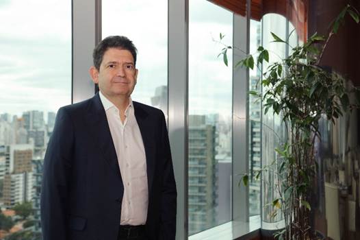 Executivo de negócios em ambiente corporativo com vista urbana ao fundo, destacando profissionalismo e liderança no setor ambiental e mercantil.
