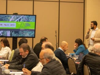 Painel de apresentação em conferência ambiental com participante falando ao microfone e audiência atenta, promovendo discussão sobre sustentabilidade e gestão ambiental.