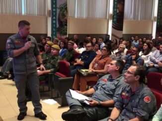 Profissional apresentando palestra para público em evento ambiental, promovendo conscientização e uso sustentável de recursos naturales no setor industrial.