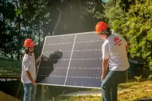 Instalação de painel solar fotovoltaico ao ar livre por equipe técnica em área ambientalmente protegida, promovendo energia renovável e sustentabilidade.
