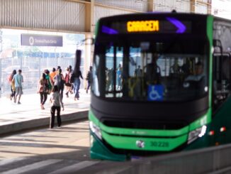 Transportes públicos ecológicos no centro da cidade com pessoas aguardando e utilizando ônibus sustentável.