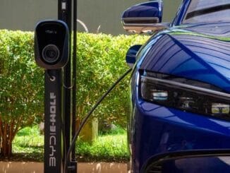 Carro elétrico azul carregando na estação de energia sustentável, promovendo transporte ecológico e inovação em mobilidade limpa; ideal para um futuro mais verde e sustentável.