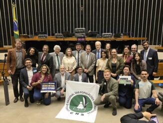 Representantes do CNNS durante reunião legislativa, promovendo direitos ambientais e populações tradicionais, em ambiente oficial de parlamento com bandeira brasileira ao fundo.
