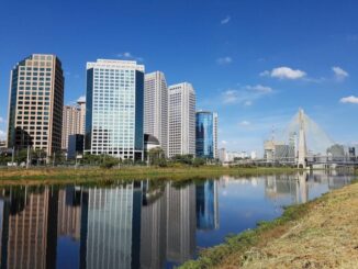 Arranha-céus modernos no centro financeiro de uma cidade com rio refletindo os prédios, cenário urbano sustentável e inovação ambiental, representando desenvolvimento ecológico e crescimento urbano.