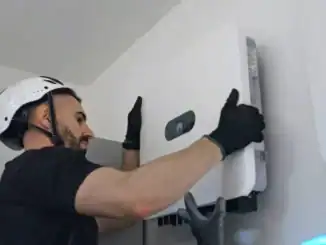 Painel de controle de sistema de energia solar fotovoltaica sendo instalado por técnico em ambiente residencial.